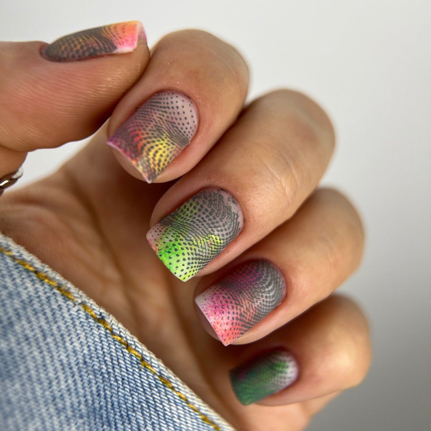 Close-up of a hand with colorful gradient nail art on a blurred background