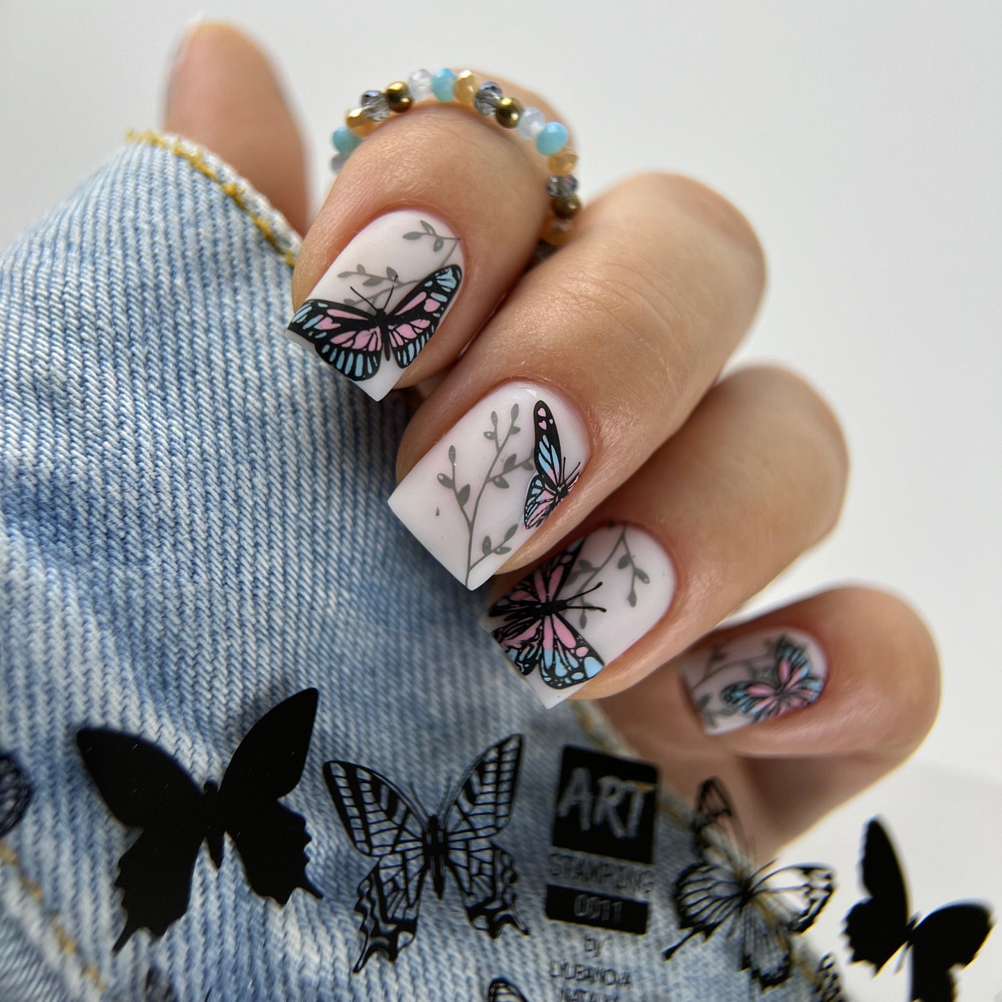 Nails with butterfly design on a denim fabric background