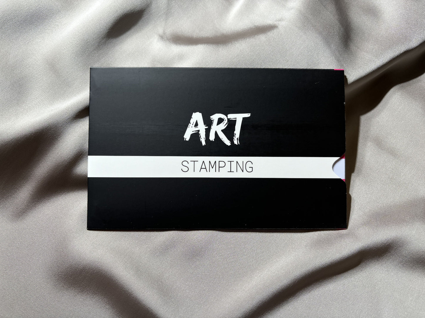 Black box with 'STAMPING ART' text on a light fabric background