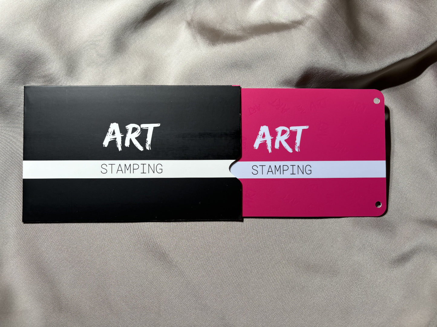 Two art stamping tools with black, red, and white design on a gray fabric background.