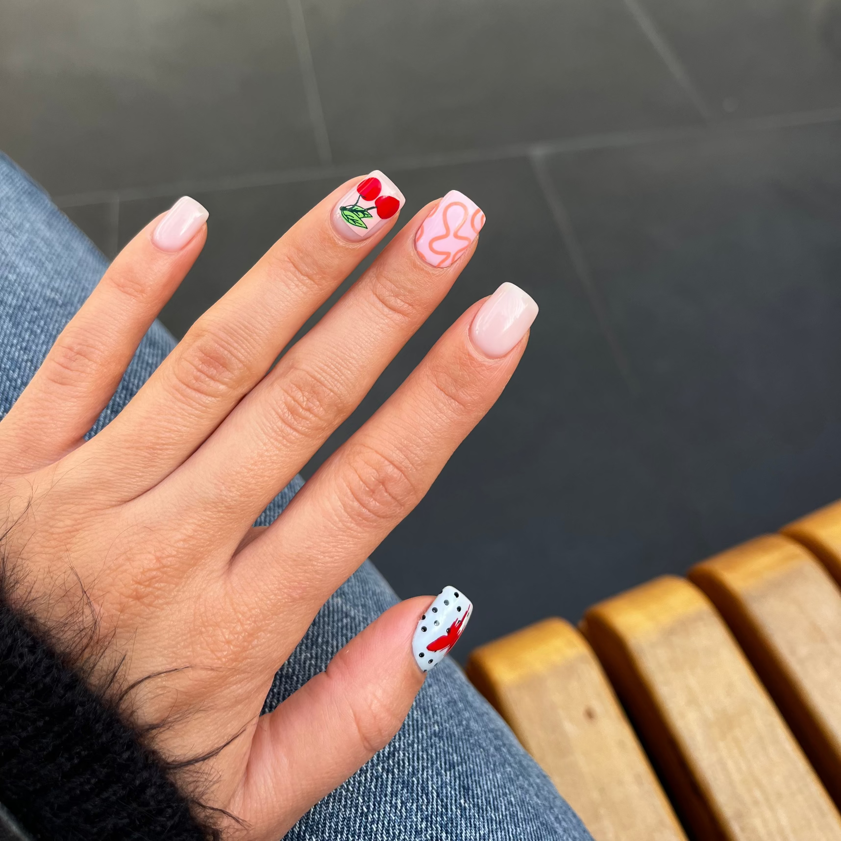 Hand with decorated nails in front of a blurred outdoor background