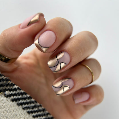 Hand with pink and gold nail design on a neutral background