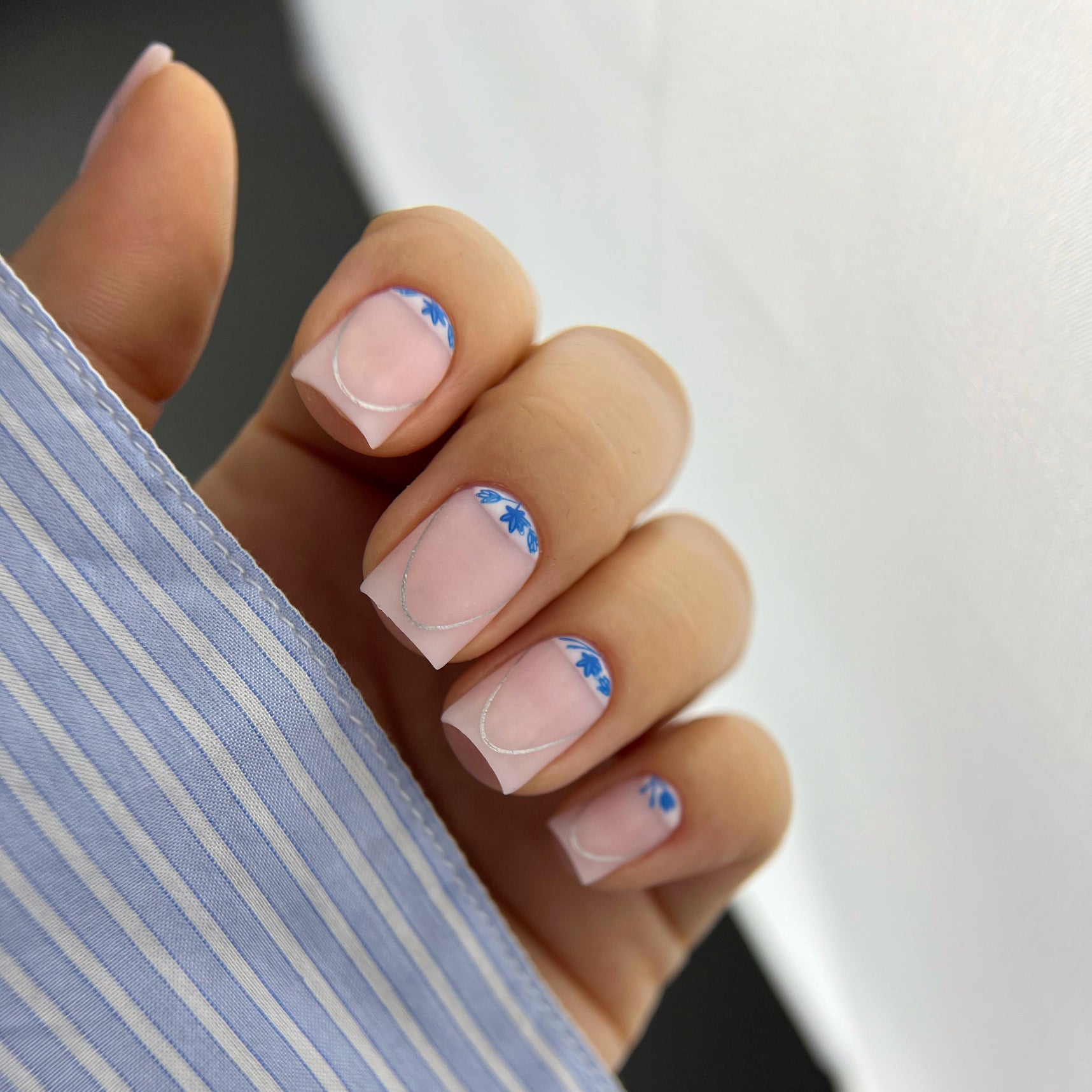 Close-up of a hand with blue nail art holding a striped fabric