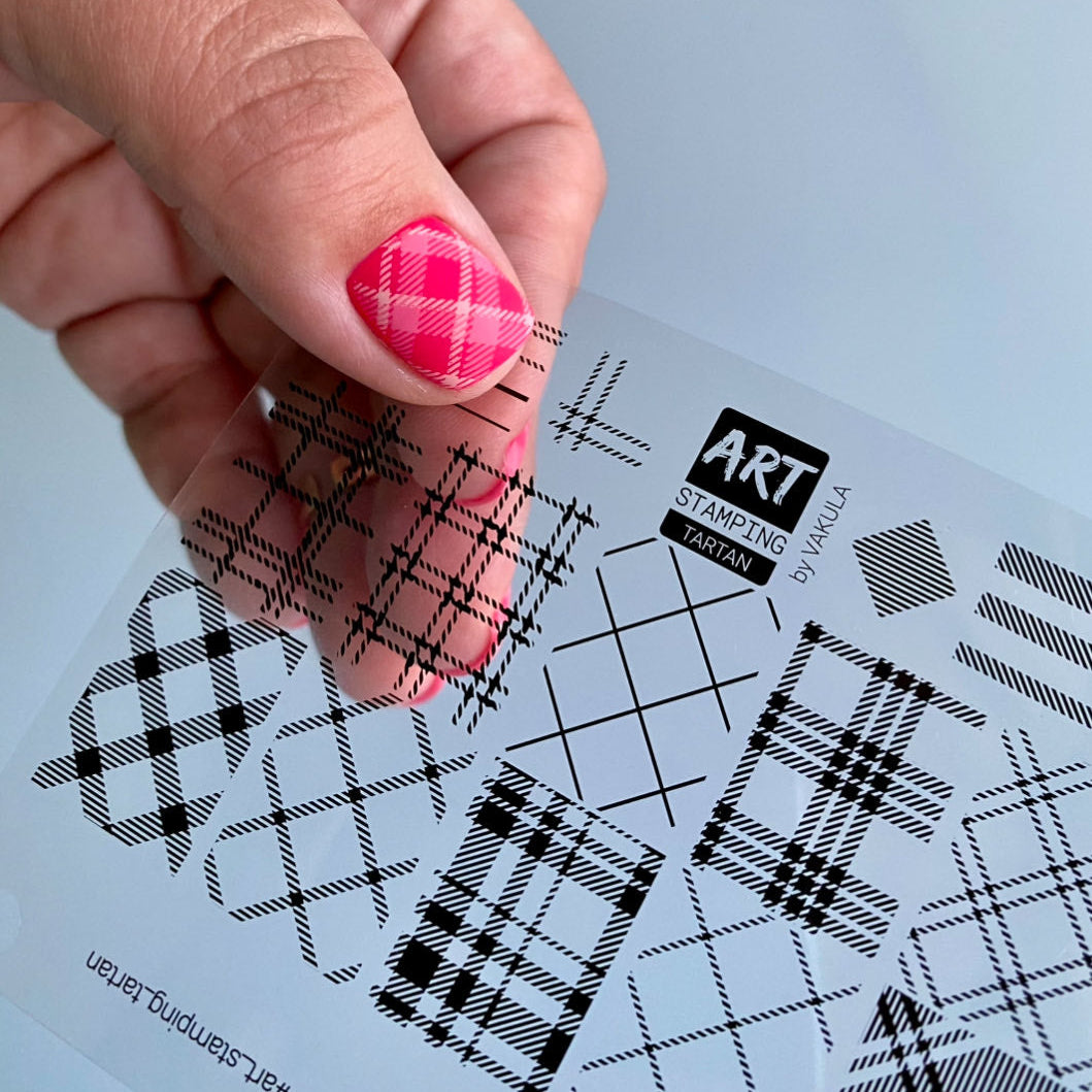 Hand holding a tartan patterned film for checking how design will look on nail before applying it