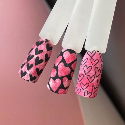 Nails with pink and black heart pattern on a blurred background