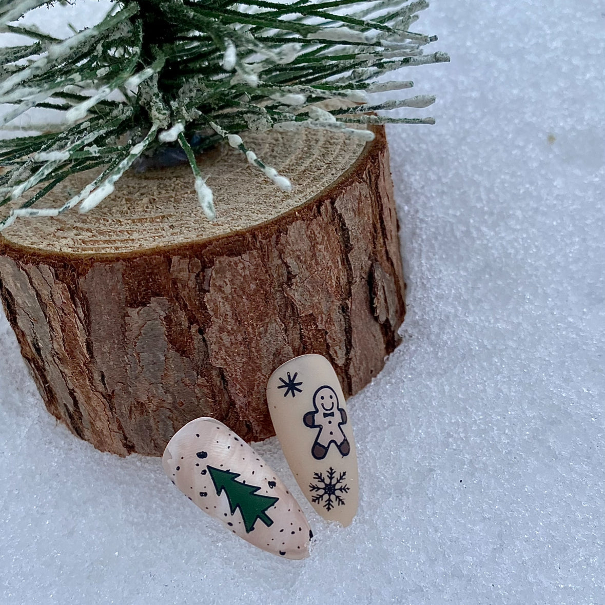Two decorative stones with winter-themed designs on a snowy background