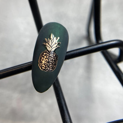Nail with green polish and gold pineapple design on nail tips