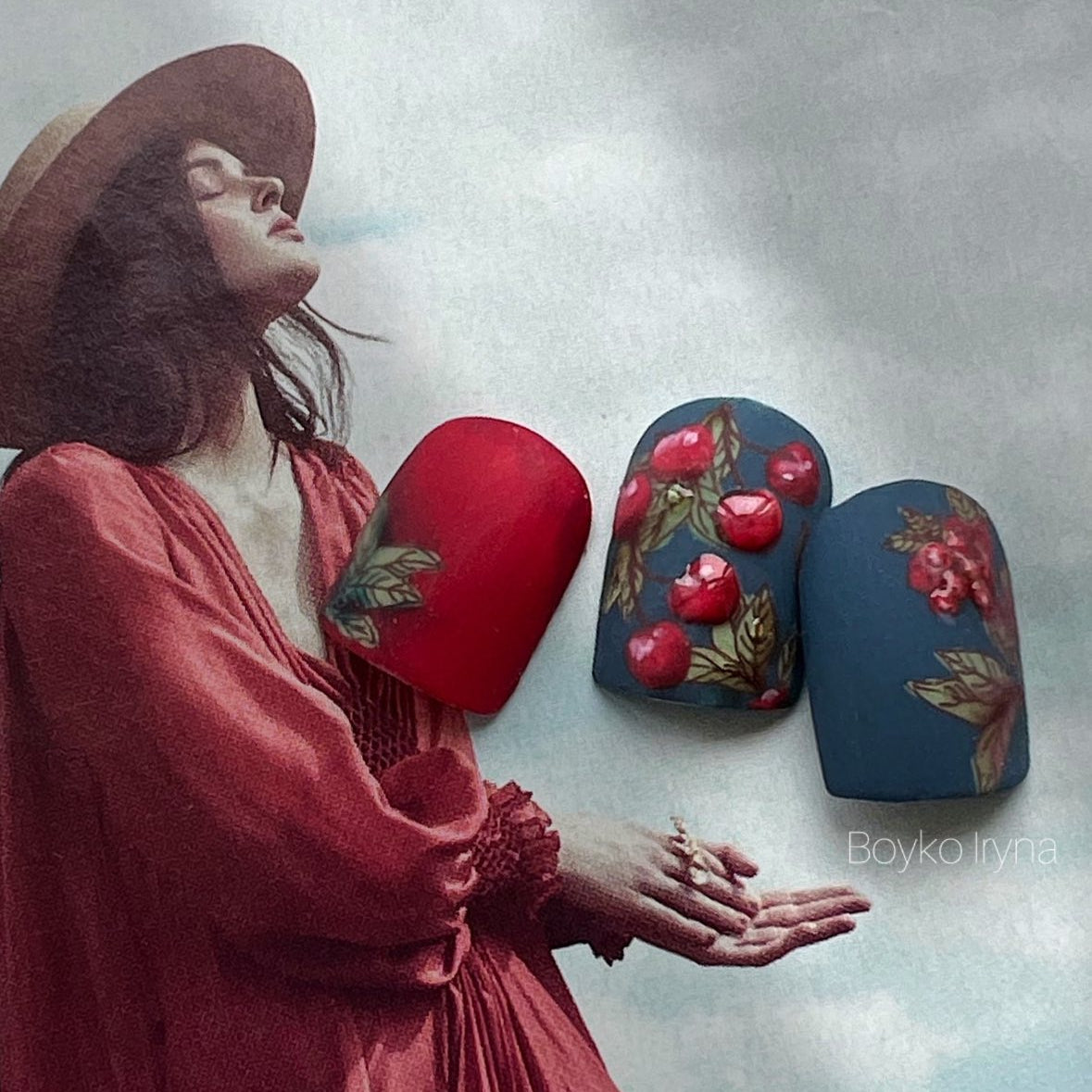  Three nail tips with floral and apple designs laying  on top of magazine cover with a woman in a red dress