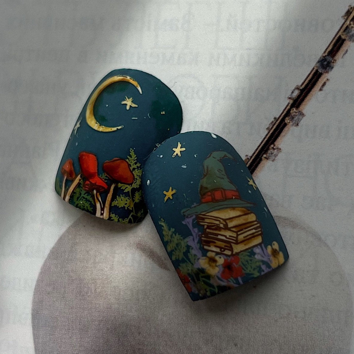 Two blue nail tips with fairy tale Halloween designs on a white background