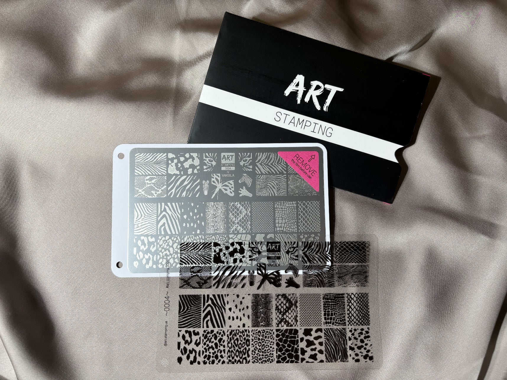 Two stencils with various patterns and a black box labeled 'STAMPS' on a light fabric background.