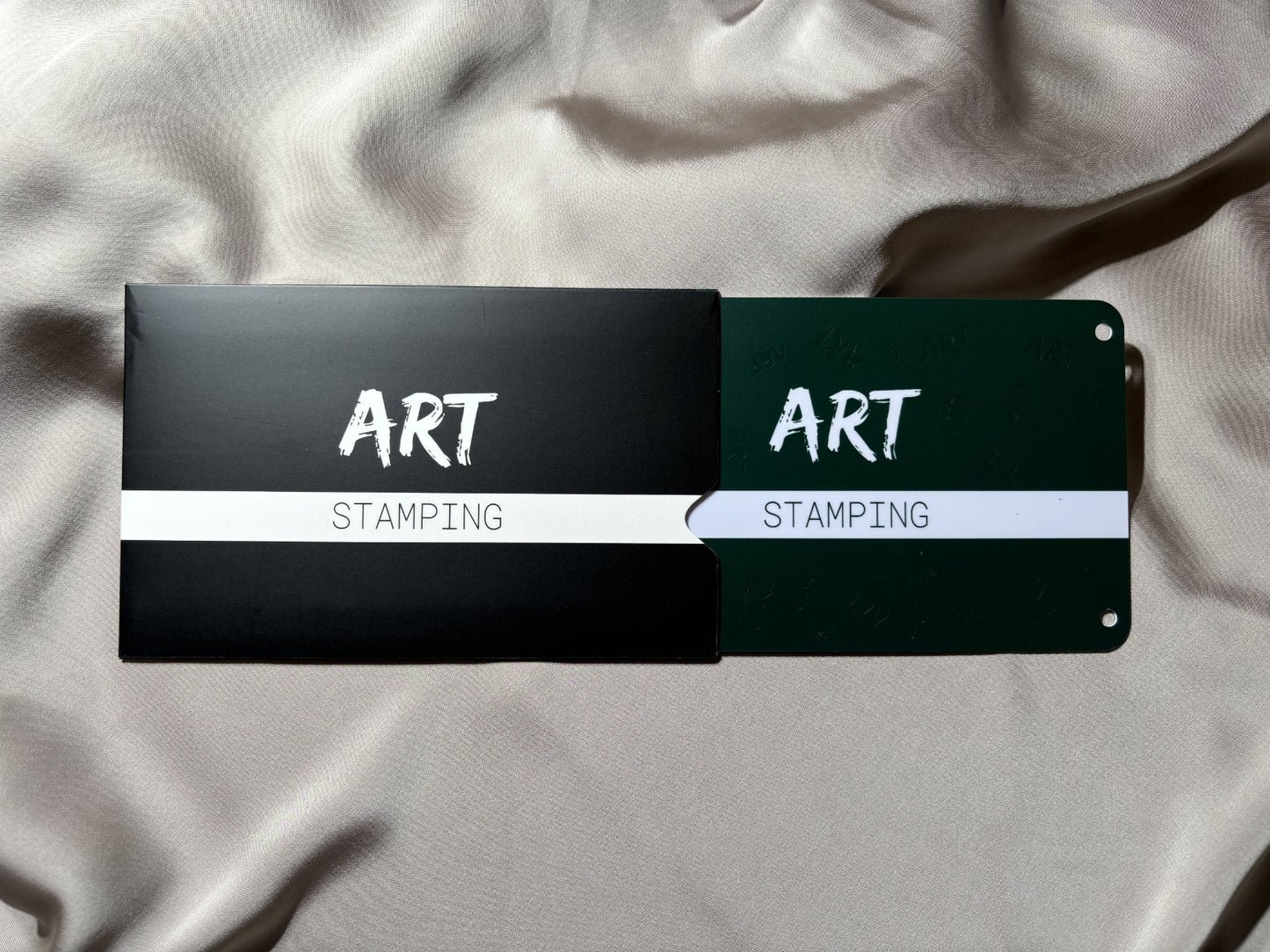 Unpacking nail art stamping plats with the brand name ART Stamping on package and plate, positioned on a textured fabric surface.