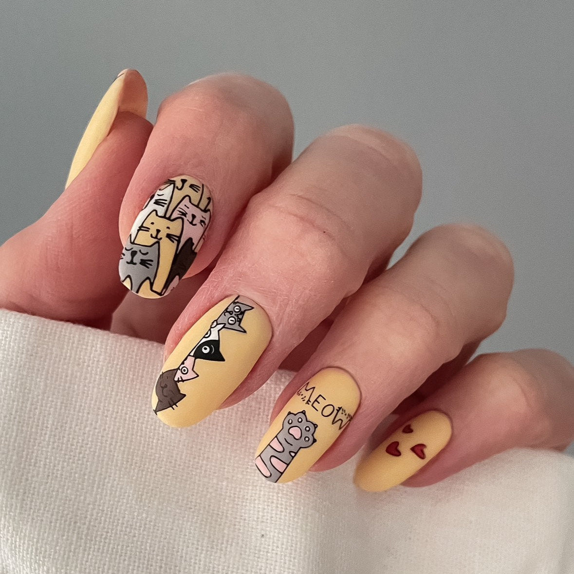Nails with cat-themed designs on a neutral background