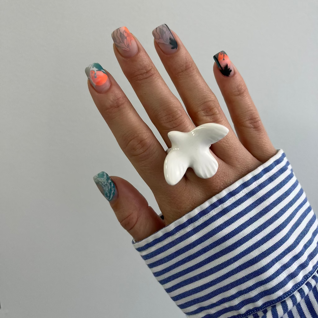 Hand wearing a white butterfly ring with striped sleeve on a plain background