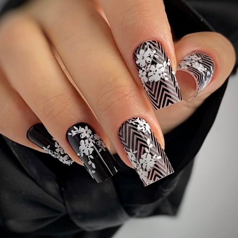 Close-up of a hand with black and white patterned nails.