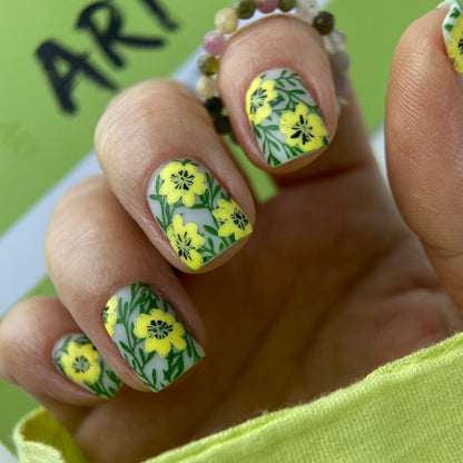 Nails with yellow floral design on a green background