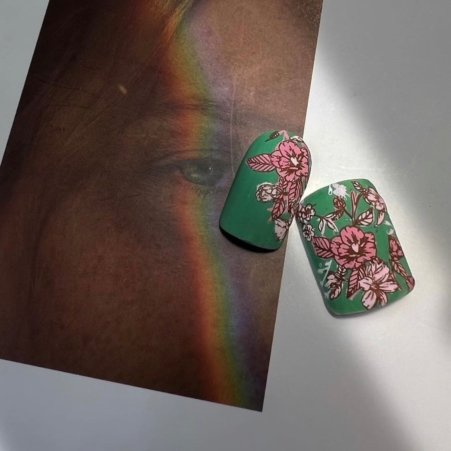 Floral nail designs on green nails with a rainbow and portrait background