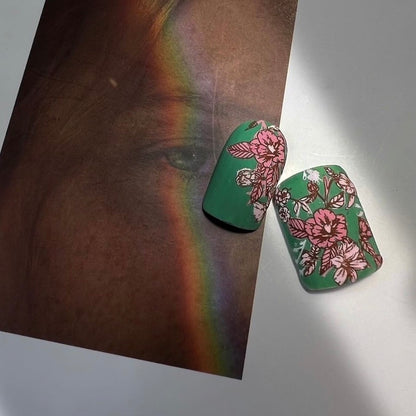 Floral nail designs on green nails with a rainbow and portrait background