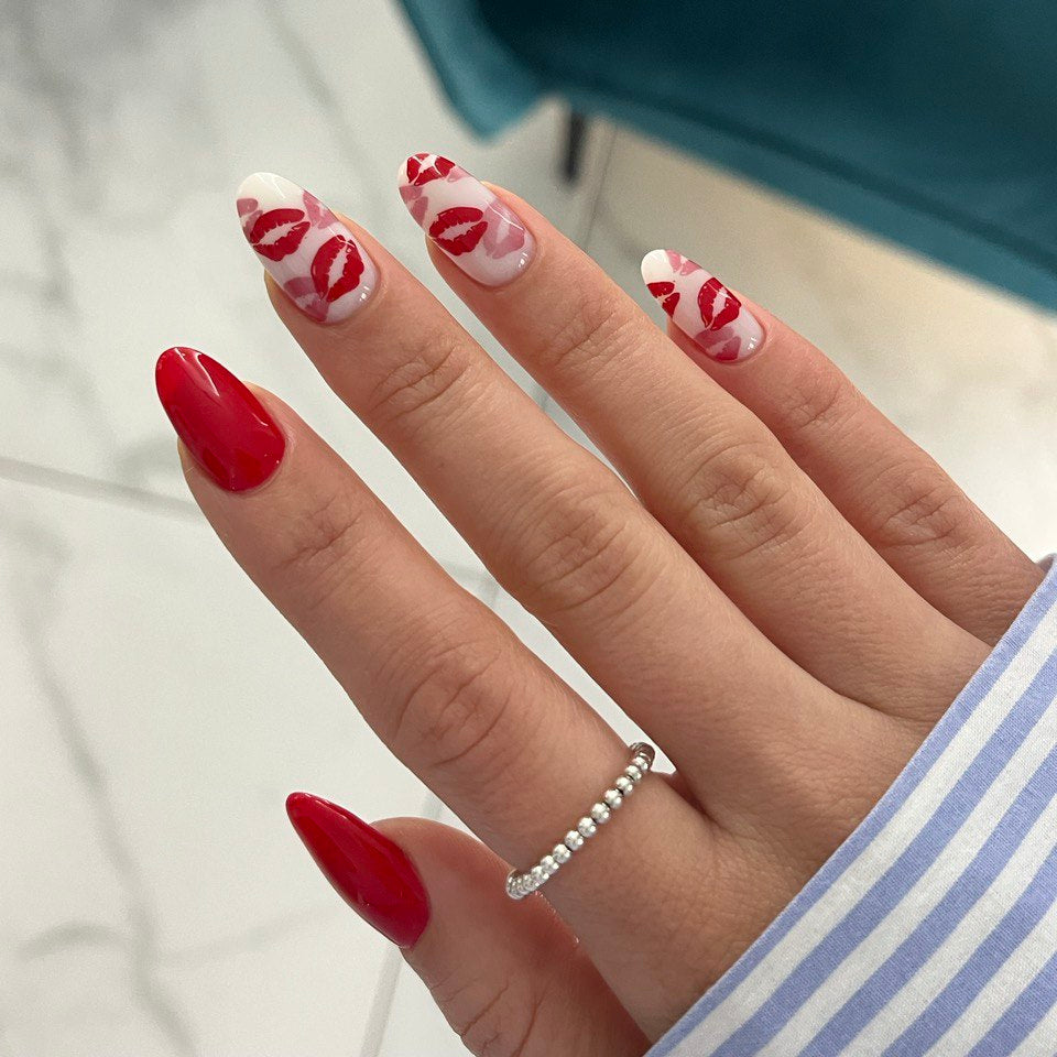 Hand with red and white nail art on a blurred background