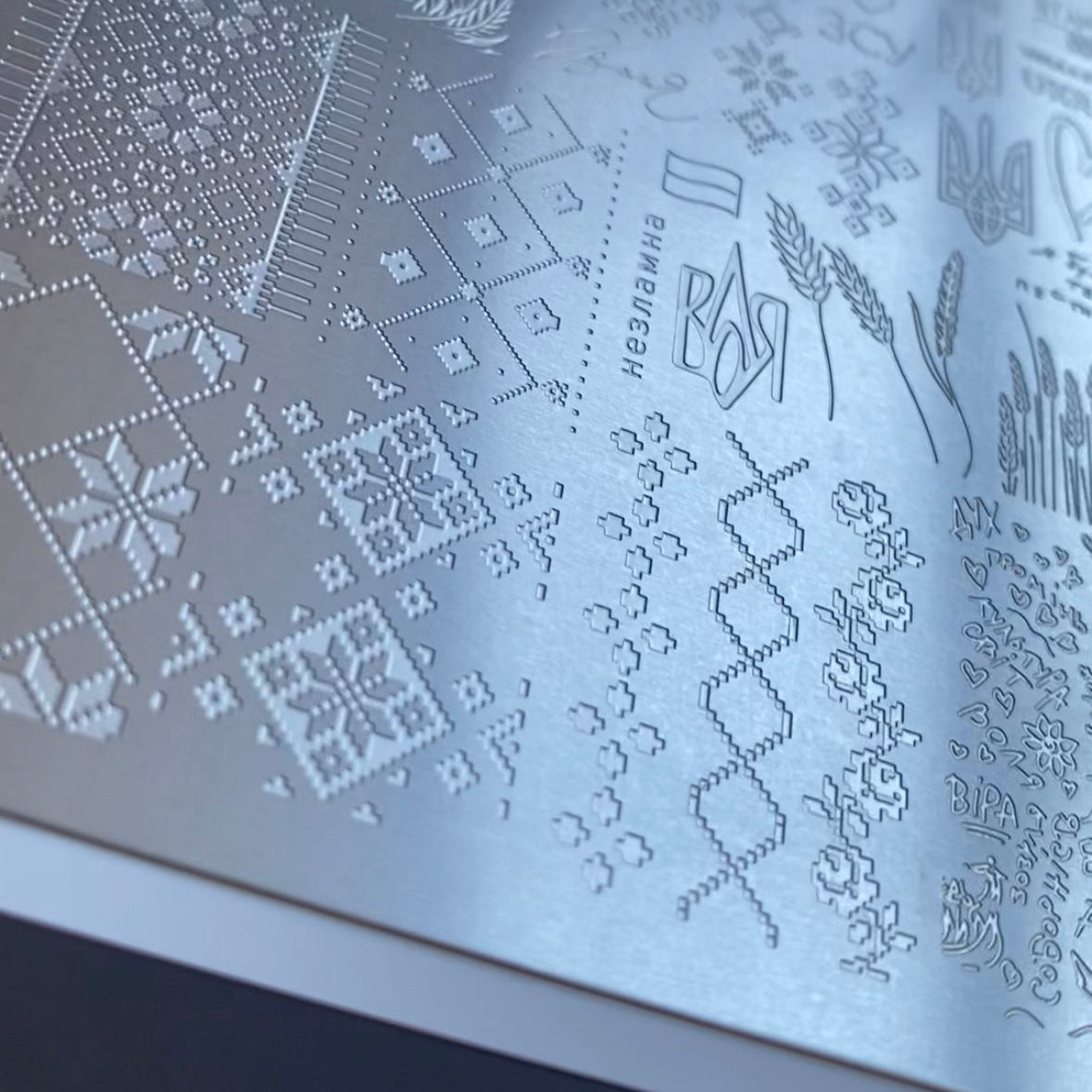 Metallic embossed pattern on a surface with text and designs.