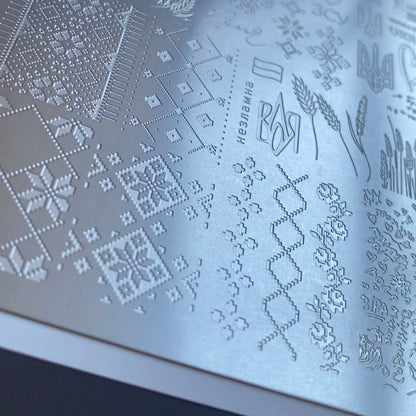 Metallic embossed pattern on a surface with text and designs.